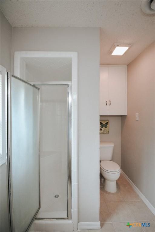 full bathroom with tile patterned floors, a stall shower, toilet, and a textured ceiling