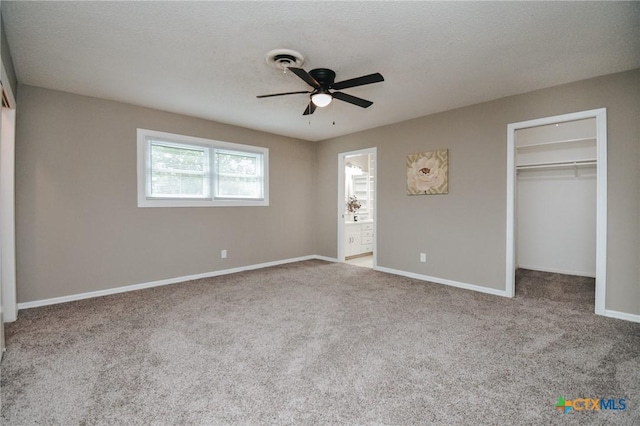 unfurnished bedroom featuring baseboards, visible vents, carpet floors, a spacious closet, and a textured ceiling