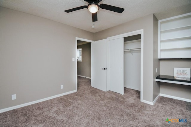 unfurnished bedroom featuring baseboards, carpet, built in desk, and a textured ceiling