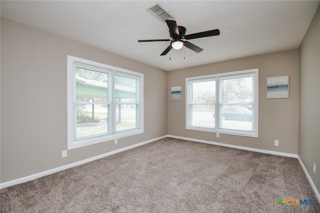 carpeted empty room featuring a textured ceiling, baseboards, visible vents, and ceiling fan