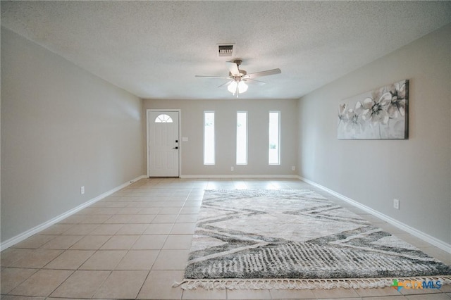 foyer entrance featuring light tile patterned flooring, baseboards, a textured ceiling, and ceiling fan