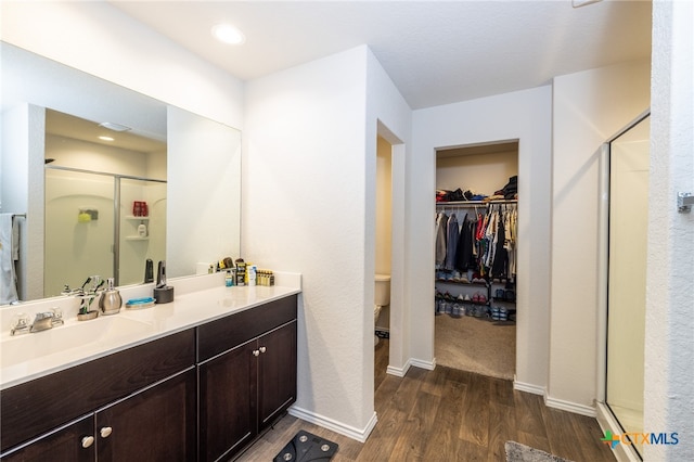 bathroom featuring wood-type flooring, vanity, toilet, and an enclosed shower