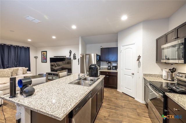 kitchen with appliances with stainless steel finishes, dark brown cabinets, sink, hardwood / wood-style flooring, and an island with sink