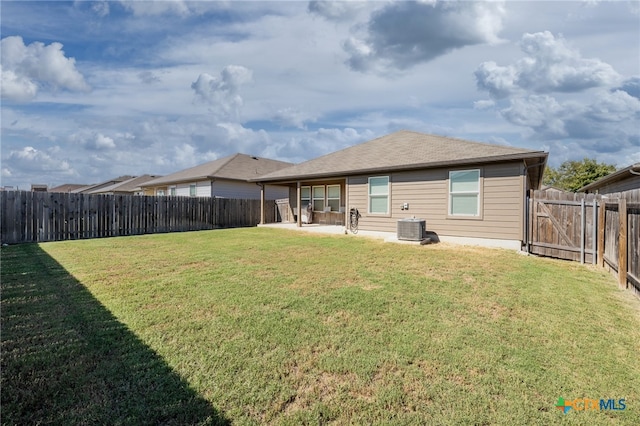 rear view of property featuring a yard, cooling unit, and a patio area