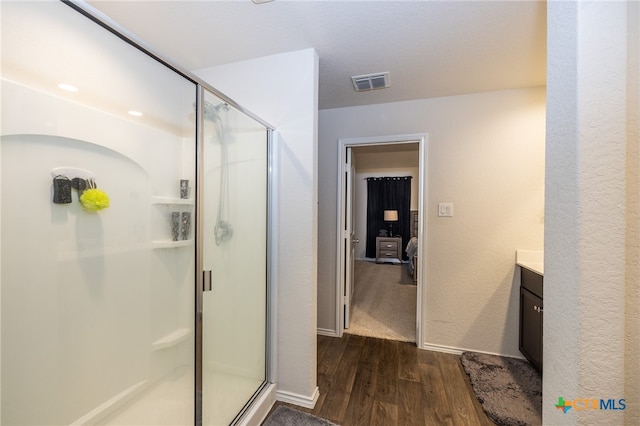 bathroom with hardwood / wood-style flooring, vanity, and walk in shower