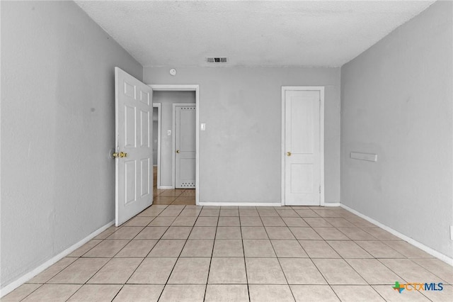 unfurnished bedroom featuring a textured ceiling and light tile patterned flooring