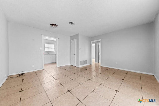 tiled spare room featuring a textured ceiling