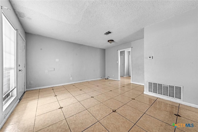 unfurnished room featuring light tile patterned floors and a textured ceiling