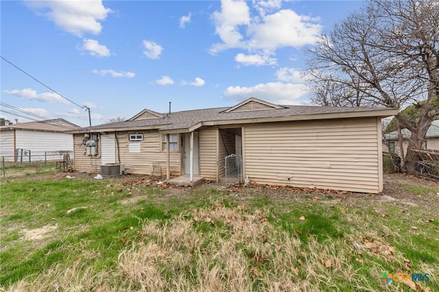 back of house with central AC unit and a lawn