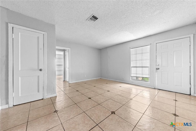 tiled empty room with a textured ceiling