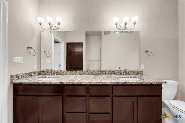 bathroom featuring vanity, an inviting chandelier, and toilet