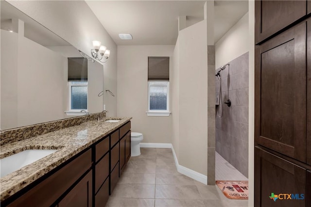 bathroom with vanity, tile patterned flooring, toilet, and tiled shower