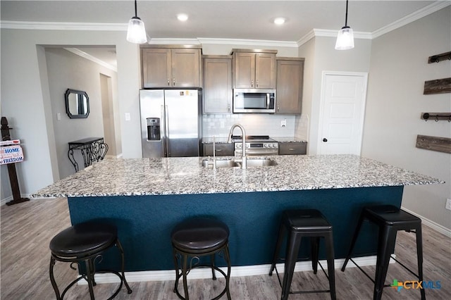 7709 Purvis St, Temple, TX 76502 - kitchen featuring stainless steel appliances, a sink, an island with sink, wood finished floors, and a breakfast bar