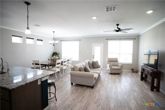7709 Purvis St, Temple, TX 76502 - living room with light wood-type flooring, crown molding, a chandelier, ceiling fan, and baseboards