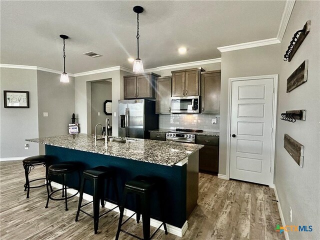 7709 Purvis St, Temple, TX 76502 - kitchen with stainless steel appliances, a sink, light wood finished floors, a kitchen breakfast bar, and tasteful backsplash