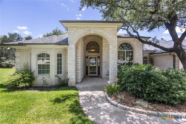 402 Prospector Trl, Harker Heights, TX 76548 - view of exterior entry featuring brick siding, a yard, roof with shingles, and stone siding