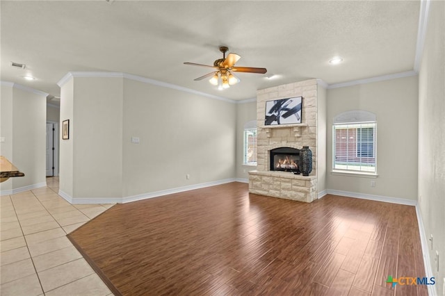 402 Prospector Trl, Harker Heights, TX 76548 - unfurnished living room with ceiling fan, a stone fireplace, crown molding, and light wood-type flooring