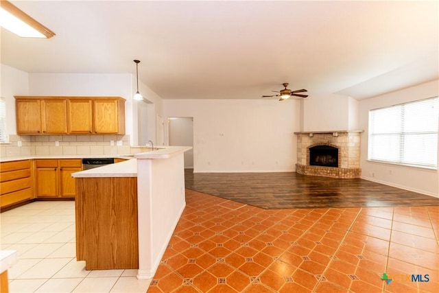 kitchen featuring light tile patterned flooring, a peninsula, tasteful backsplash, and light countertops