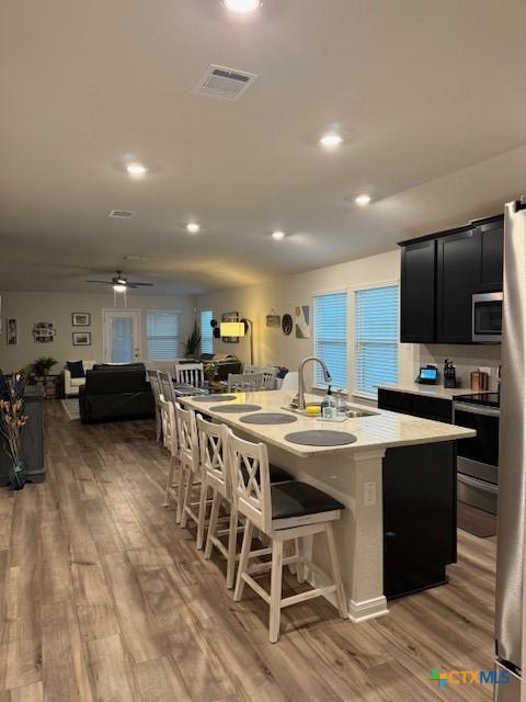 3154 Charyn Way, New Braunfels, TX 78132 - kitchen with a sink, appliances with stainless steel finishes, light wood-style flooring, a kitchen breakfast bar, and recessed lighting