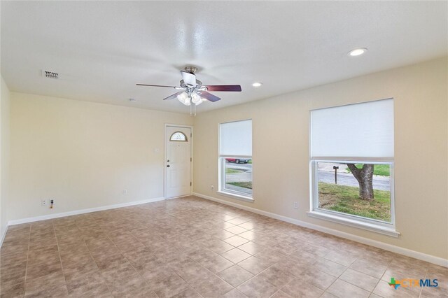 spare room with ceiling fan and light tile patterned floors