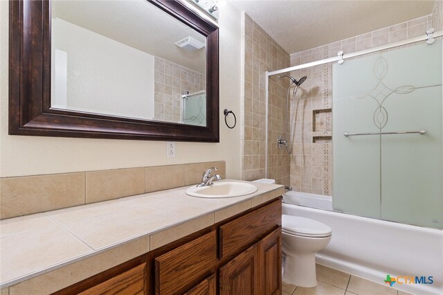 full bathroom featuring a textured ceiling, vanity, enclosed tub / shower combo, tile patterned flooring, and toilet