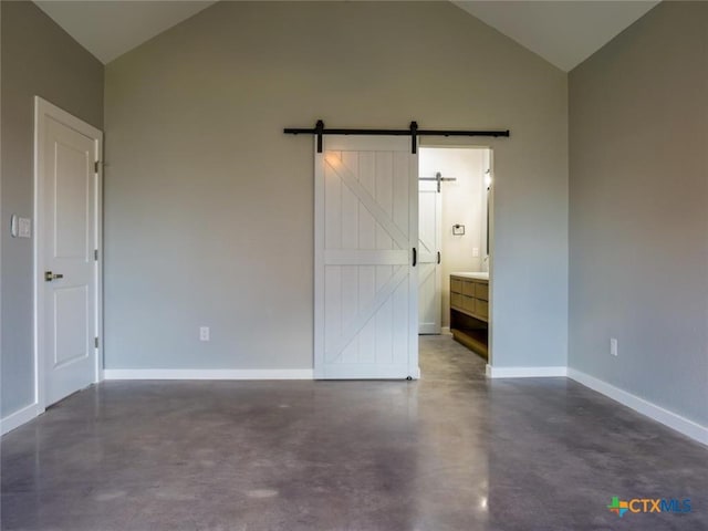 unfurnished bedroom featuring a barn door, connected bathroom, and lofted ceiling