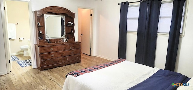 bedroom featuring connected bathroom and light hardwood / wood-style floors