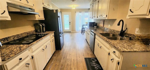 kitchen featuring sink, black electric stovetop, white cabinets, stainless steel dishwasher, and dark stone counters