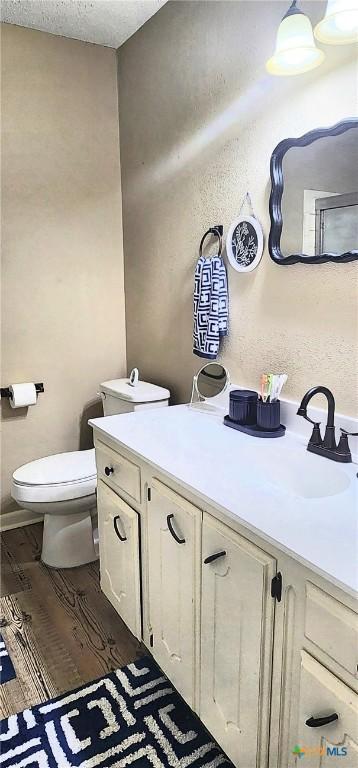 bathroom featuring hardwood / wood-style flooring, vanity, a textured ceiling, and toilet