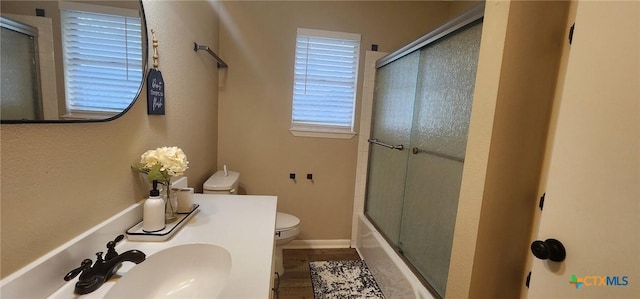 full bathroom featuring vanity, combined bath / shower with glass door, and toilet