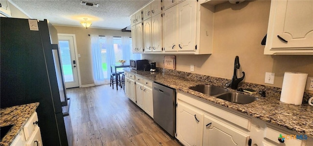 kitchen with white cabinetry, sink, dark stone countertops, stainless steel appliances, and a textured ceiling