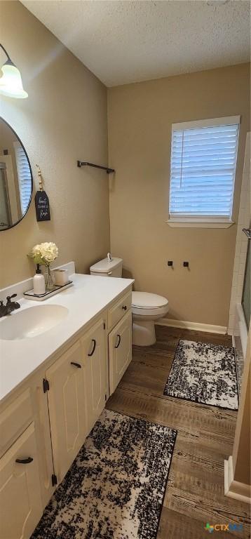 bathroom featuring vanity, hardwood / wood-style floors, toilet, and a textured ceiling