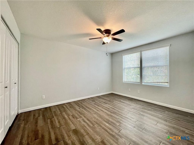 110 Rush Hvn, San Marcos, TX 78666 - unfurnished bedroom with a textured ceiling, a closet, dark wood-style floors, and baseboards
