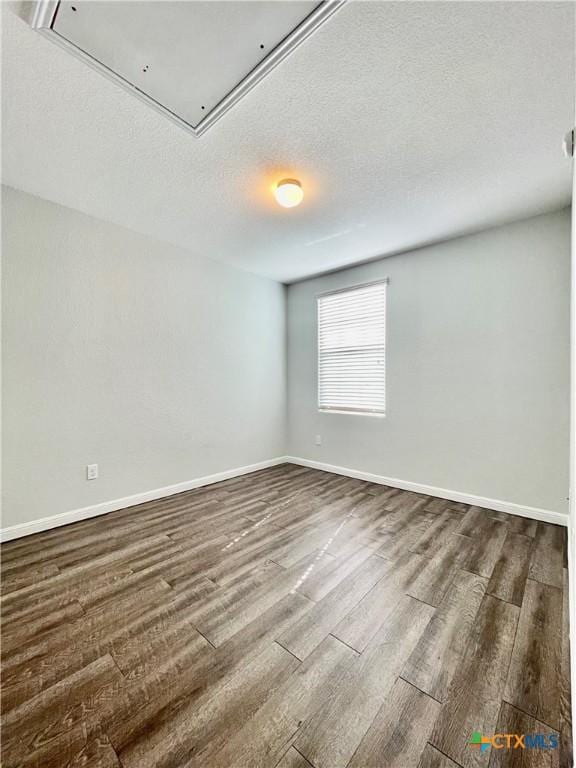110 Rush Hvn, San Marcos, TX 78666 - empty room featuring baseboards, attic access, a textured ceiling, and dark wood-type flooring