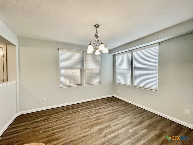 110 Rush Hvn, San Marcos, TX 78666 - unfurnished dining area with baseboards, a chandelier, a textured ceiling, and wood finished floors