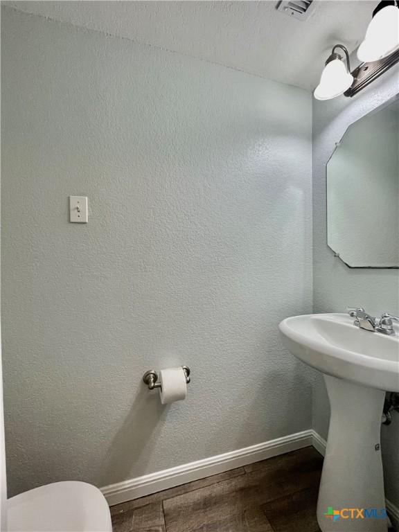110 Rush Hvn, San Marcos, TX 78666 - half bath with wood finished floors, visible vents, baseboards, and toilet
