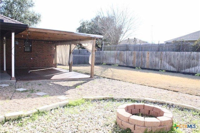 view of yard featuring a carport and an outdoor fire pit