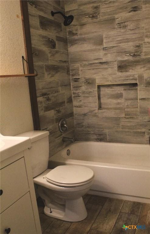 full bathroom featuring tiled shower / bath combo, toilet, and vanity