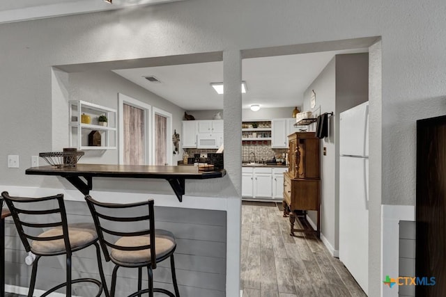 332 W Klein St, Seguin, TX 78155 - kitchen featuring a textured wall, dark countertops, a kitchen bar, open shelves, and light wood-style flooring