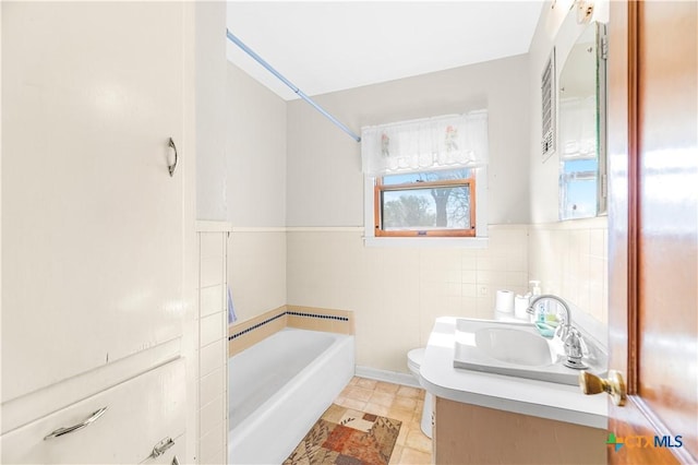 bathroom with vanity, tile patterned flooring, toilet, tile walls, and a tub