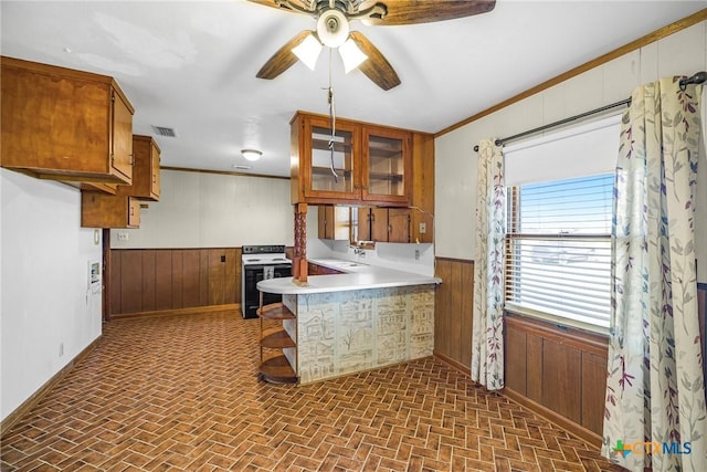 kitchen featuring white range with electric stovetop, wood walls, kitchen peninsula, and sink