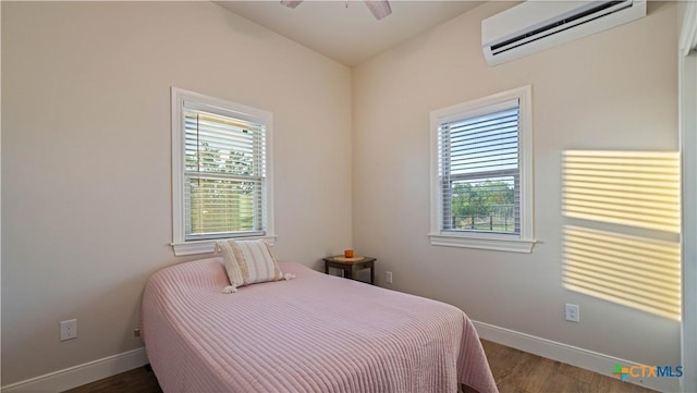 bedroom featuring baseboards, a ceiling fan, a wall mounted AC, and wood finished floors