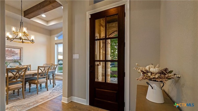 doorway with baseboards, an inviting chandelier, and wood finished floors
