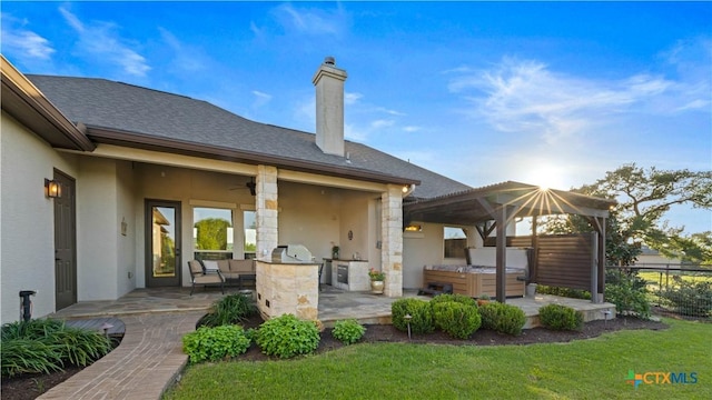back of property with area for grilling, ceiling fan, a patio area, a gazebo, and stucco siding