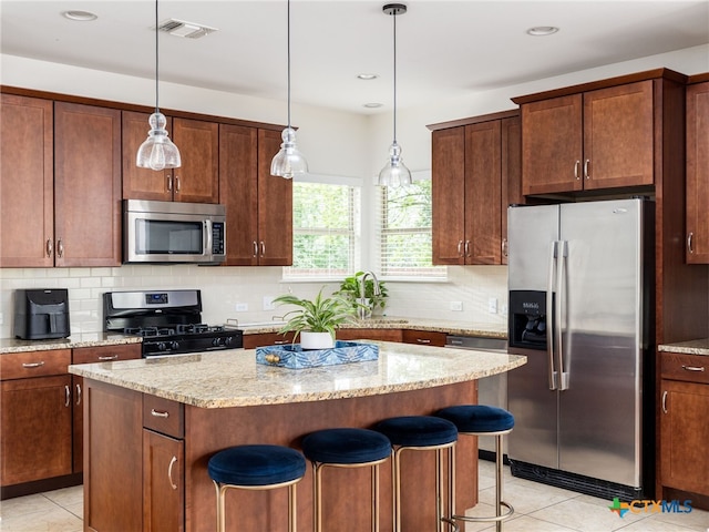1200 Marcy St, Austin, TX 78745 - kitchen featuring appliances with stainless steel finishes, light tile patterned flooring, a center island, a kitchen bar, and recessed lighting
