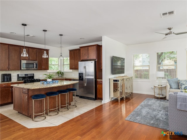 1200 Marcy St, Austin, TX 78745 - kitchen featuring appliances with stainless steel finishes, a kitchen island, decorative backsplash, light wood-style floors, and recessed lighting