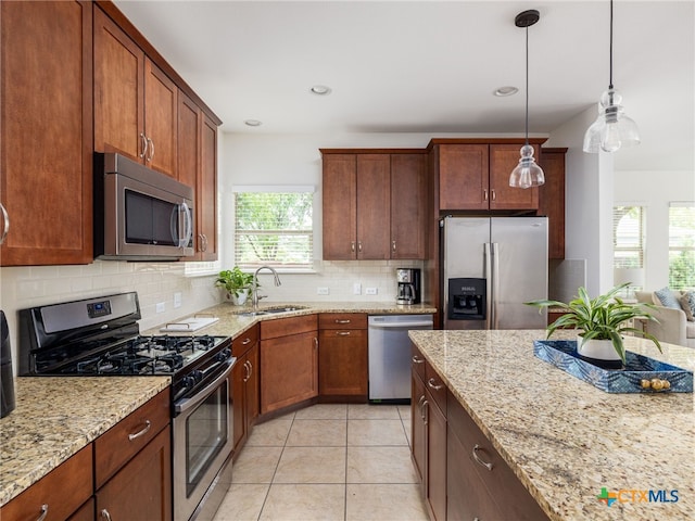 1200 Marcy St, Austin, TX 78745 - kitchen featuring appliances with stainless steel finishes, a sink, backsplash, light stone counters, and hanging light fixtures