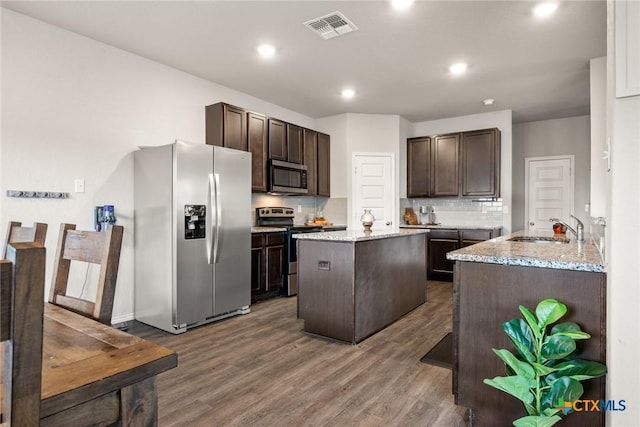 kitchen with sink, tasteful backsplash, dark brown cabinets, a kitchen island, and stainless steel appliances