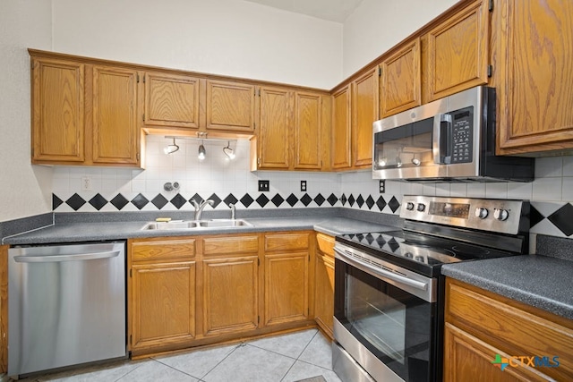 kitchen with tasteful backsplash, sink, light tile patterned floors, and appliances with stainless steel finishes