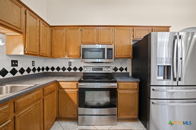 kitchen with tasteful backsplash, light tile patterned flooring, and appliances with stainless steel finishes